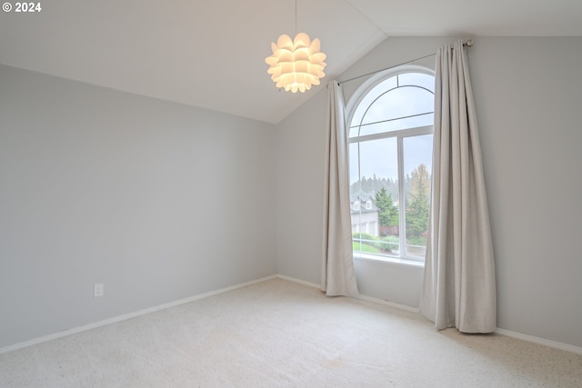 spare room featuring vaulted ceiling, carpet flooring, and an inviting chandelier