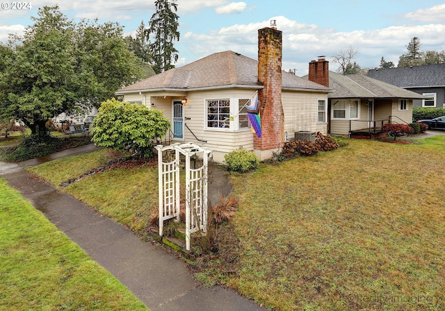 view of front of house with a front lawn and central air condition unit