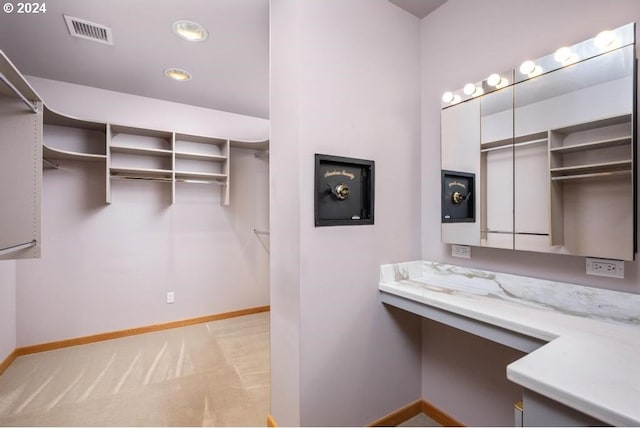 walk in closet featuring light carpet and built in desk