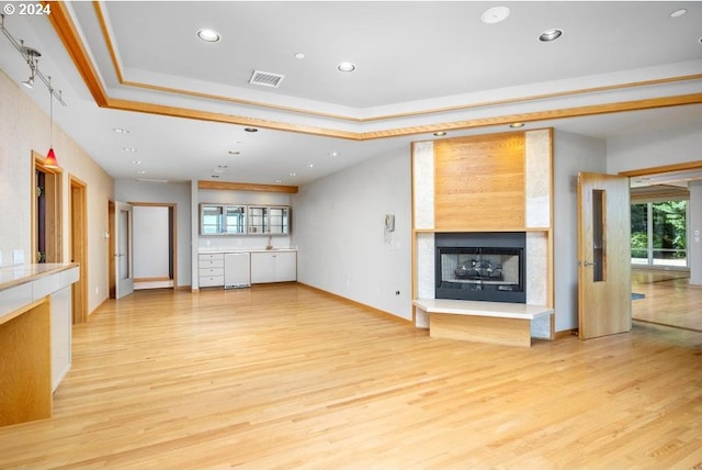 unfurnished living room featuring light hardwood / wood-style floors and a raised ceiling