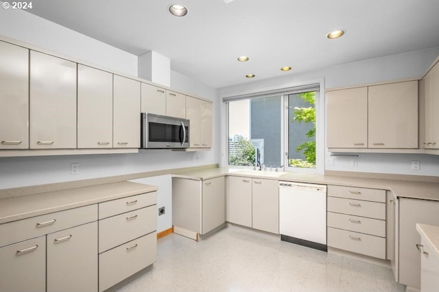 kitchen featuring dishwasher, sink, and cream cabinetry