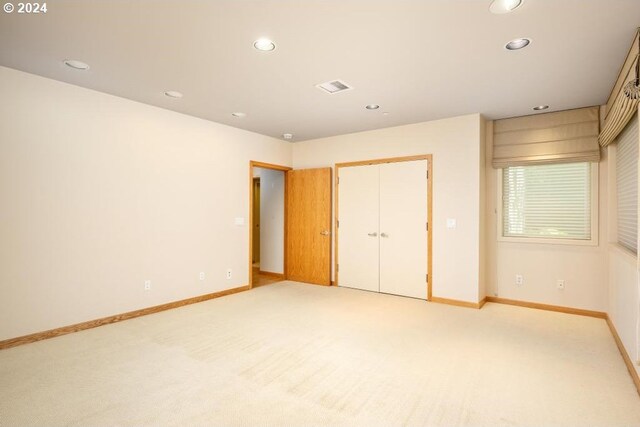 unfurnished bedroom with light colored carpet and a closet