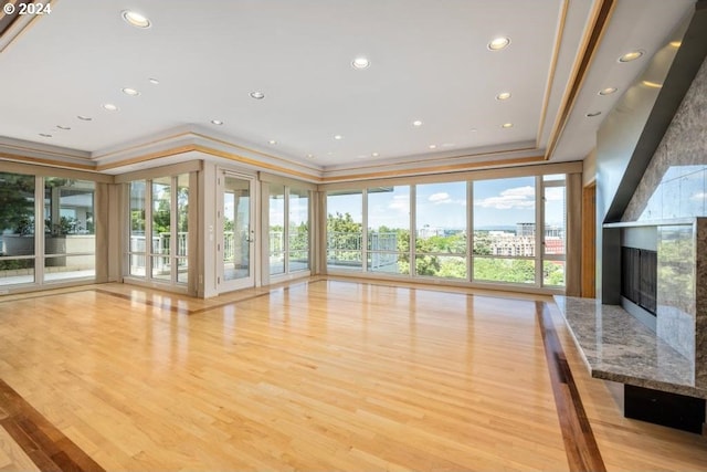 unfurnished living room with a premium fireplace, ornamental molding, and light hardwood / wood-style flooring