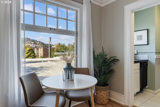 dining space featuring light hardwood / wood-style floors, ornamental molding, and a healthy amount of sunlight