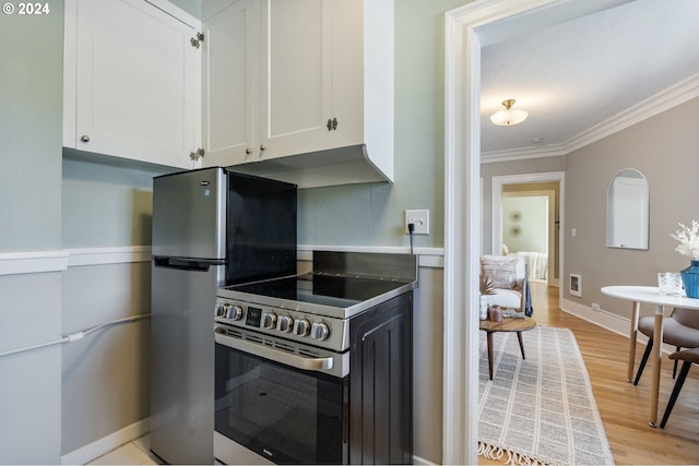 kitchen with appliances with stainless steel finishes, white cabinets, light wood-type flooring, and ornamental molding