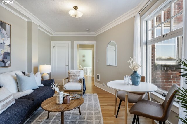 living area with crown molding, hardwood / wood-style flooring, and a textured ceiling