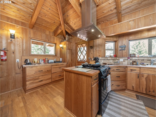 kitchen with wooden walls, light wood-type flooring, island exhaust hood, and black range with gas cooktop