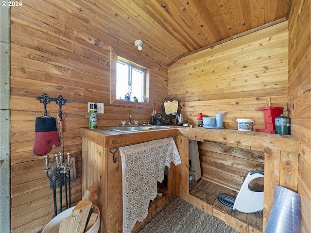 interior space with wooden walls, sink, wooden ceiling, and lofted ceiling