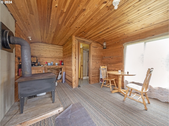 interior space with wooden walls, a wood stove, and wooden ceiling