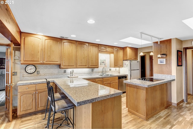 kitchen with white refrigerator, a skylight, dishwasher, and a kitchen island