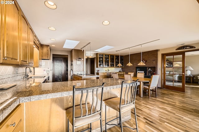 kitchen featuring sink, decorative light fixtures, a kitchen breakfast bar, kitchen peninsula, and a skylight