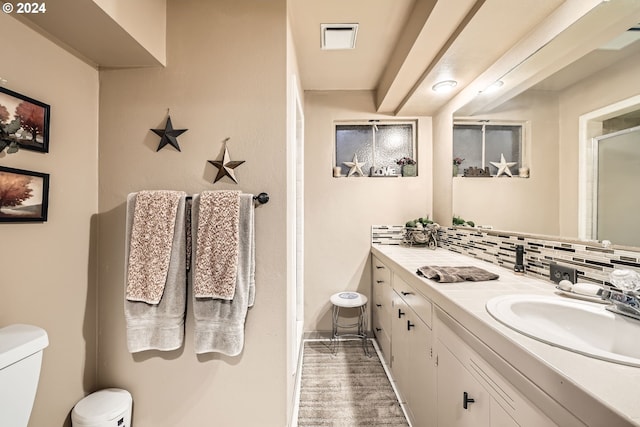 bathroom featuring vanity, hardwood / wood-style flooring, decorative backsplash, and toilet