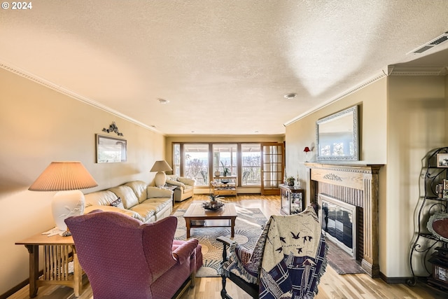 living room with a brick fireplace, a textured ceiling, ornamental molding, and light hardwood / wood-style flooring