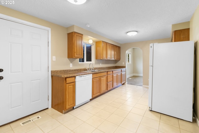 213 Engle Ave, Molalla, OR 97038 - kitchen with white appliances, arched walkways, a textured ceiling, brown cabinets, and light tile patterned flooring