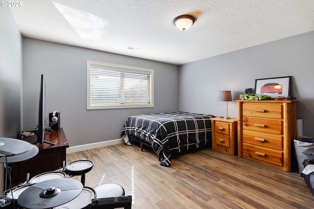 bedroom with hardwood / wood-style floors and a textured ceiling