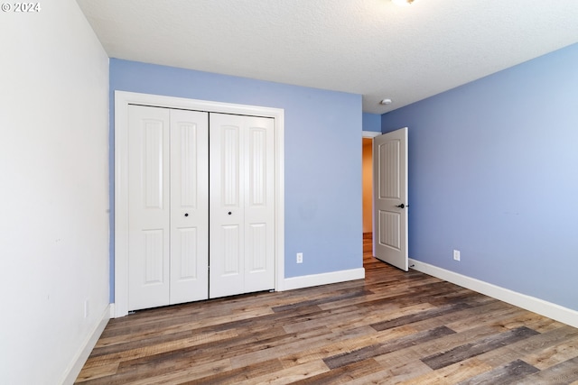 unfurnished bedroom with a textured ceiling, a closet, and dark wood-type flooring