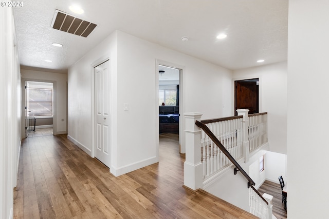 hall with light wood-type flooring and a textured ceiling