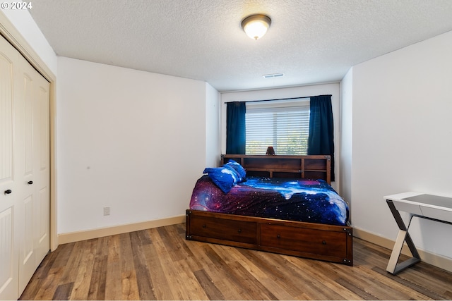 bedroom with a closet, hardwood / wood-style floors, and a textured ceiling