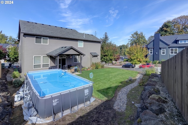 back of property with a fenced in pool and a yard