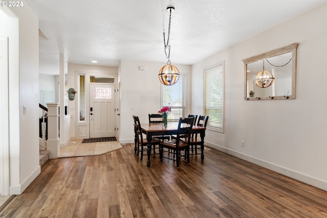 dining area with hardwood / wood-style flooring, a notable chandelier, and a textured ceiling