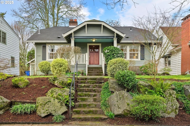 craftsman house featuring a chimney, a porch, and roof with shingles