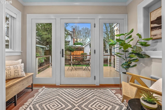 doorway to outside with ornamental molding and tile patterned floors