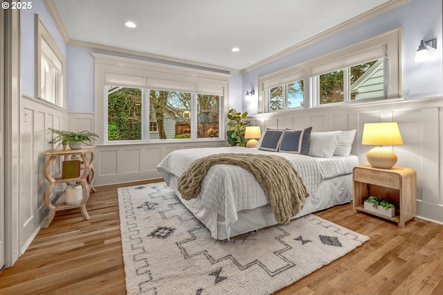 bedroom featuring ornamental molding, recessed lighting, a decorative wall, and wood finished floors