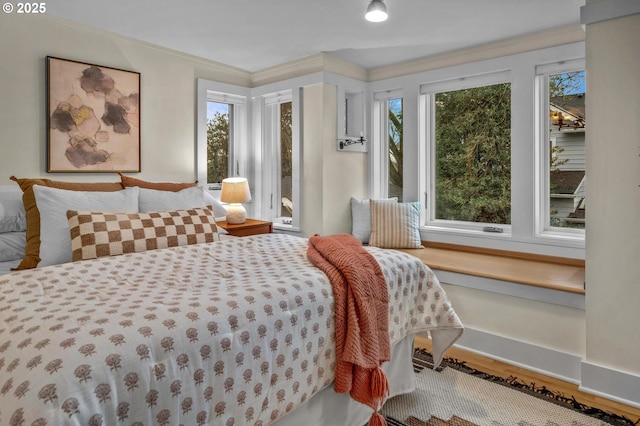 bedroom featuring crown molding, baseboards, and wood finished floors