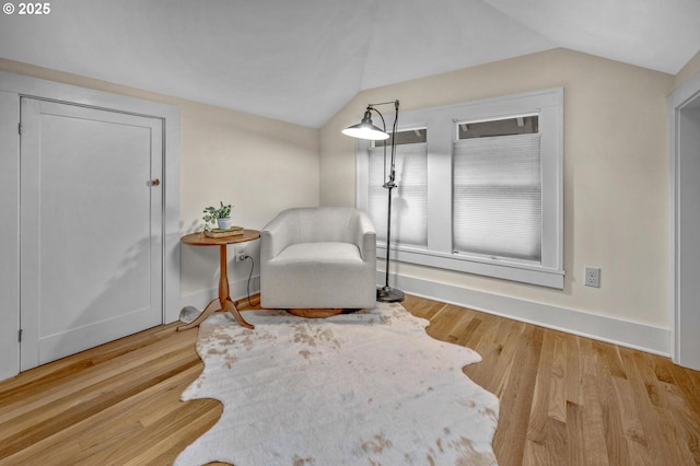 living area featuring lofted ceiling, baseboards, and wood finished floors