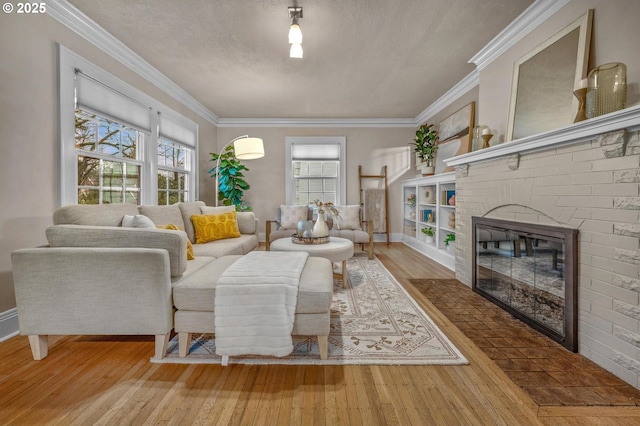 living area with ornamental molding, hardwood / wood-style floors, a textured ceiling, and a brick fireplace