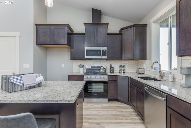 kitchen with tasteful backsplash, lofted ceiling, a breakfast bar, stainless steel appliances, and light hardwood / wood-style floors