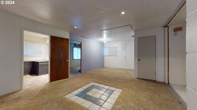 spare room with light colored carpet and a textured ceiling