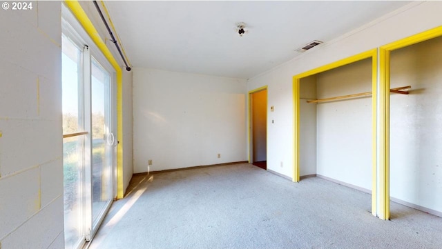 unfurnished bedroom featuring light colored carpet and multiple closets