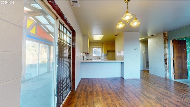 kitchen featuring dark hardwood / wood-style flooring, a notable chandelier, kitchen peninsula, decorative light fixtures, and decorative backsplash