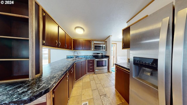 kitchen featuring a textured ceiling, dark stone countertops, sink, and appliances with stainless steel finishes