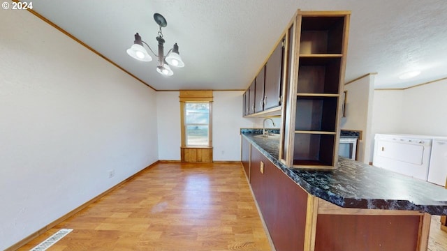 kitchen featuring a chandelier, washing machine and dryer, a textured ceiling, and light hardwood / wood-style flooring