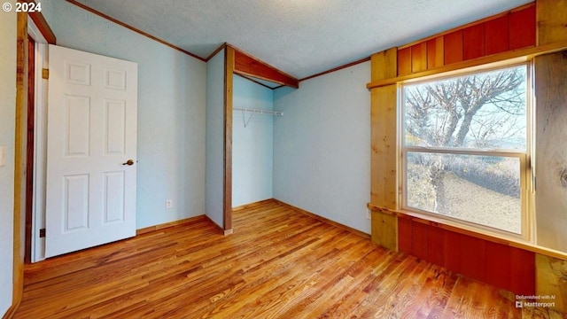 unfurnished bedroom with multiple windows, a closet, a textured ceiling, and light wood-type flooring