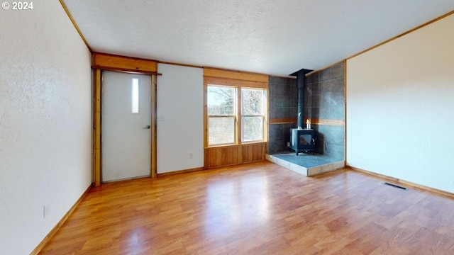 unfurnished living room featuring a wood stove, wood-type flooring, and a textured ceiling