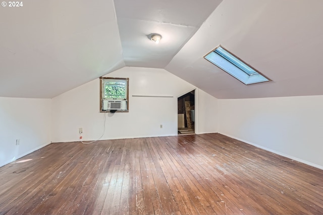 additional living space featuring cooling unit, wood-type flooring, and lofted ceiling with skylight