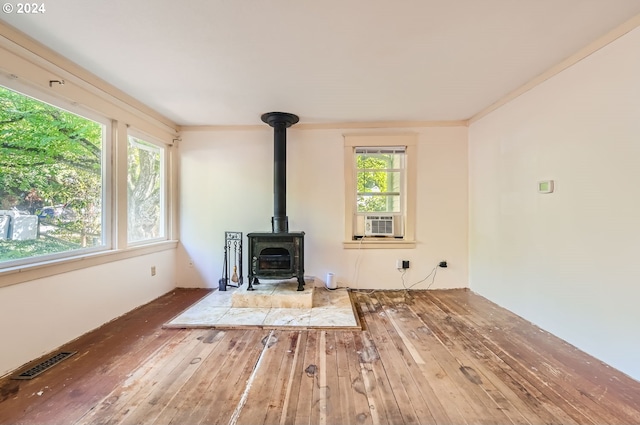 living room featuring a wood stove, ornamental molding, hardwood / wood-style floors, and cooling unit