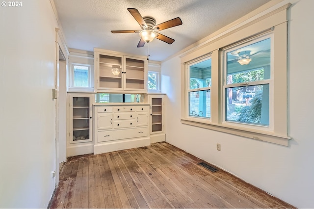 unfurnished room with ceiling fan, light hardwood / wood-style floors, a textured ceiling, and a healthy amount of sunlight