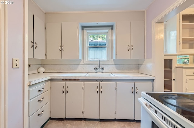 kitchen featuring white range with electric cooktop, white cabinetry, and sink