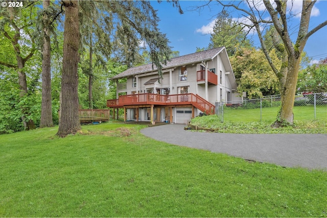 view of front of property featuring a wooden deck, a front lawn, and a garage