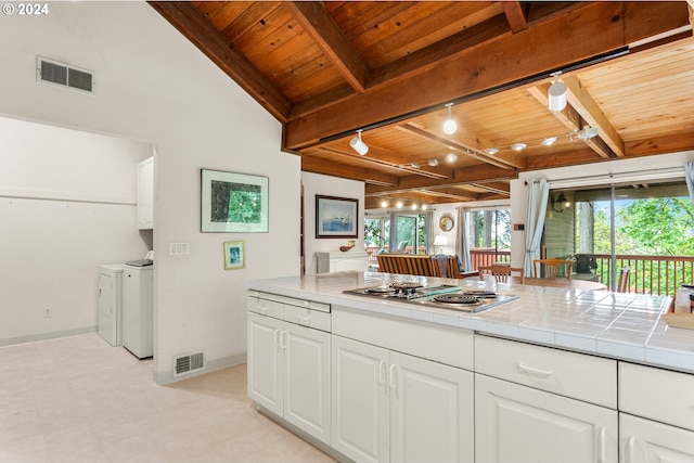 kitchen featuring tile counters, washing machine and dryer, white cabinets, and wooden ceiling