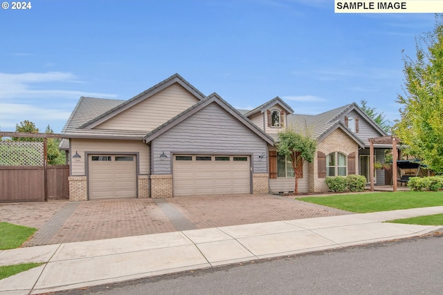 view of front of house with brick siding, a front lawn, fence, decorative driveway, and a garage