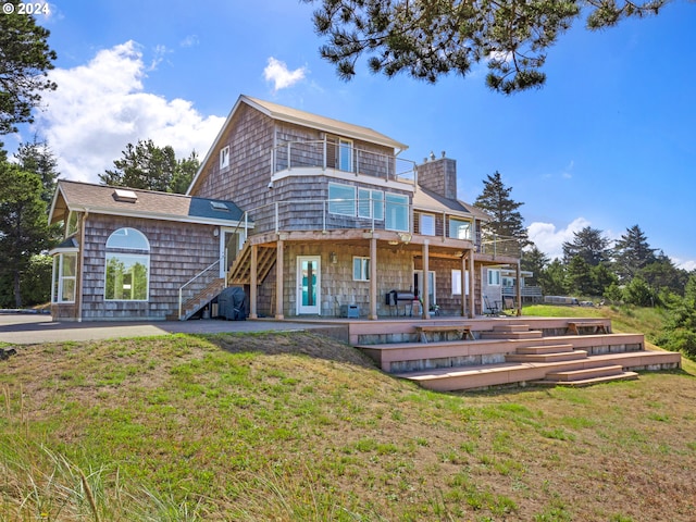 rear view of property featuring a lawn, a patio area, and a deck