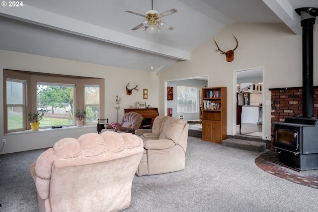 carpeted living room with ceiling fan, lofted ceiling with beams, and a wood stove