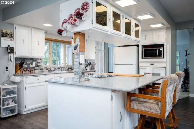 kitchen with white cabinetry, sink, tasteful backsplash, dark hardwood / wood-style floors, and white appliances