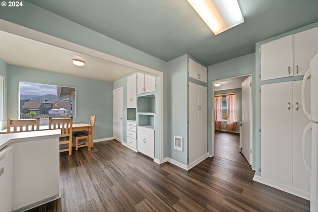 kitchen featuring a textured ceiling, dark wood-type flooring, white dishwasher, and white cabinetry