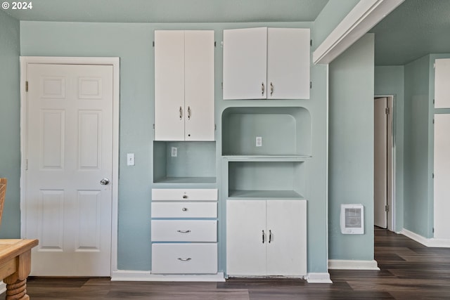 interior space featuring dark hardwood / wood-style floors, heating unit, and white cabinets